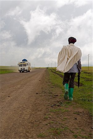 rainy season man walking - Man walking along the road during the rainy season wearing green boots and holding an umbrella, The Ethiopian Highlands, Ethiopia, Africa Stock Photo - Rights-Managed, Code: 841-02903077