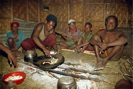 Dani men inside house, preparing dinner and playing wooden guitar, South Beliam Valley, Irian Jaya, Indonesia, Southeast Asia, Asia Foto de stock - Con derechos protegidos, Código: 841-02917577