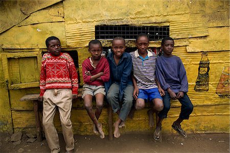 Portrait of a group of five boys, slum children, sitting on a bench outdoors, looking at the camera, Kariobangi, Nairobi, Kenya, East Africa, Africa Fotografie stock - Rights-Managed, Codice: 841-02947196