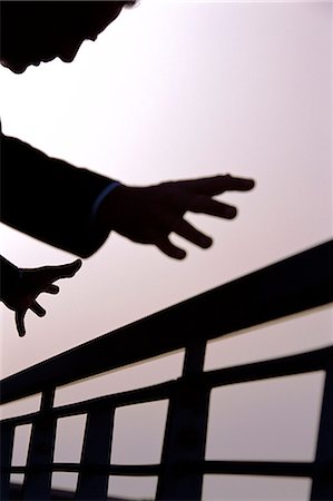 silhouette hand grasp - A business man outdoors with outstretched hands about to grasp railings Stock Photo - Rights-Managed, Code: 841-03034648