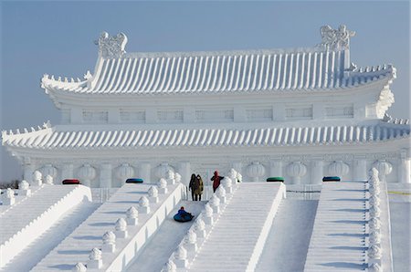 A boy slides down a giant replica sculpture of Beijing's Forbidden City at the Snow and Ice Sculpture Festival on Sun Island Park, Harbin, Heilongjiang Province, Northeast China, China, Asia Foto de stock - Direito Controlado, Número: 841-03055927