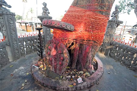 Temple shrine to Shakti, the sun god, daubed by pilgrims with red powder, tree tied with numerous holy Hindu strings, and offerings, Sri Mahabhairab Mandir, Tezpur, Assam, India, Asia Stock Photo - Rights-Managed, Code: 841-03675436