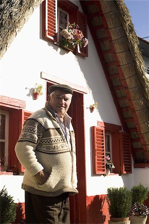 A Madeiran man stands outside of a traditional Palheiro A-frame house in the town of Santana, Madeira, Portugal, Europe Stock Photo - Rights-Managed, Code: 841-03677205