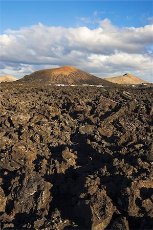 Irregular blocky lava (a'a) and cinder cones of the volcanic landscape of Timanfaya National Park, Lanzarote, Canary Islands, Spain, Atlantic Ocean, Europe Foto de stock - Con derechos protegidos, Código: 841-03677369