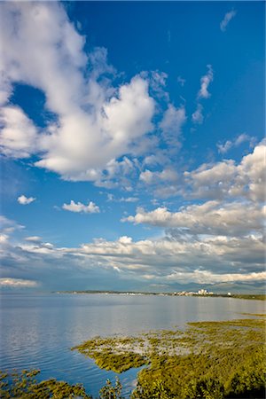 Mélange de soleil et de nuages au-dessus de l'horizon de la ville d'Anchorage et Knik Arm à marée haute, les montagnes Chugach à l'arrière-plan, le centre-sud de l'Alaska, l'été Photographie de stock - Rights-Managed, Code: 854-05974310