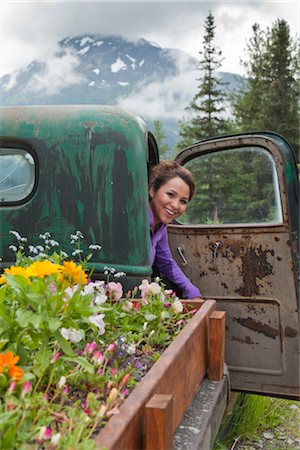 Eine junge Frau Inupiat inspiziert das Innere eines alten LKW verwandelte sich in ein Blumenbeet auf Crow Creek Mine in der Nähe von Girdwood, South Central Alaska, Sommer Stockbilder - Lizenzpflichtiges, Bildnummer: 854-05974373