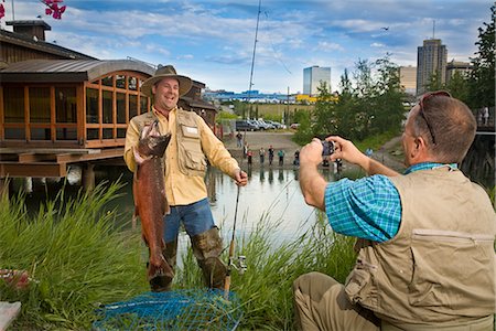 Fisherman poses with King Salmon while getting his photo taken at Ship Creek in downtown Anchorage, Alaska during Summer Stock Photo - Rights-Managed, Code: 854-02954991