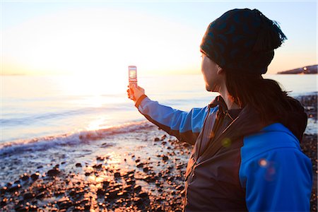 Femme utilise son téléphone cellulaire pour photographier le coucher de soleil sur le golfe de Cook sur l'isthme de Homer, Alaska Photographie de stock - Rights-Managed, Code: 854-02955931