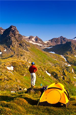 Ein Mann auf seinem Campingplatz in den Talkeetna Mountains mit kahlen Bergrücken im Hintergrund, South Central Alaska, Sommer Stockbilder - Lizenzpflichtiges, Bildnummer: 854-03361765