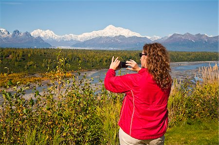 phone mountains view - Woman takes photo with IPhone of the south side of Mt. Mckinley with Chulitna River in foreground,from Denali Viewpoint South off of Parks Highway, Denali State Park, Summer, Southcentral Alaska Stock Photo - Rights-Managed, Code: 854-03362512