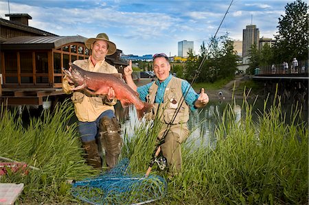 Fishermen poses with King Salmon at Ship Creek in downtown Anchorage, Alaska during Summer Foto de stock - Direito Controlado, Número: 854-03538039