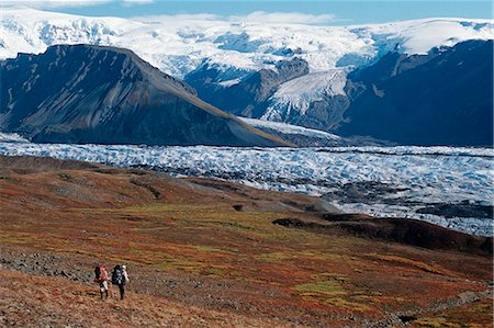 Pair of backpackers hike through the fall landscape toward Long Glacier at Wrangell-St.Elias National Park in Southcentral Alaska. Fotografie stock - Rights-Managed, Codice: 854-03538213