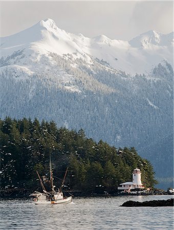 southeast - Troller heads out of the Sitka Harbor as it passes by the Rockwell Lighthouse with Mt. Longenbaugh in the background in Southeast Alaska during Winter Stock Photo - Rights-Managed, Code: 854-03538524