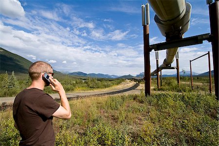 Man talking on cell phone near the Trans Alaska pipeline. Summer in Interior Alaska. Stock Photo - Rights-Managed, Code: 854-03538525