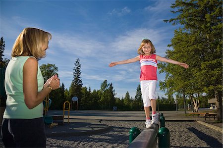 parent and child on playground - A mother watches as her young daughter walks on a  balance beam at a school playground in Anchorage, Alaska during Summer Foto de stock - Con derechos protegidos, Código: 854-03538762