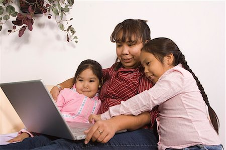 AK native children w/mother reading book & using computer together @ home Tlingit/Athabascan Foto de stock - Con derechos protegidos, Código: 854-03538873