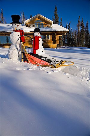 fairbanks - Large & small snowman ride on dog sled in deep snow in afternoon in front of log cabin style home Fairbanks Alaska winter Fotografie stock - Rights-Managed, Codice: 854-03539268