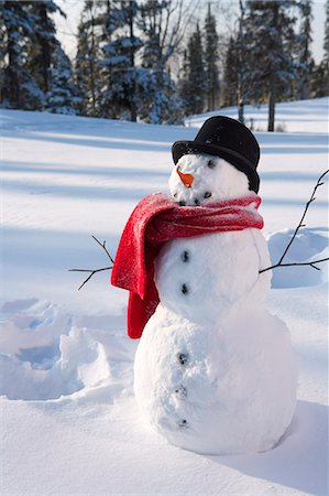 funny freezing cold photos - Snowman wearing santa hat in snowy meadow w/imprint from snow angel forest in background Alaska Winter Stock Photo - Rights-Managed, Code: 854-03539290