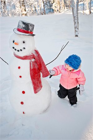 Junges Mädchen schmückt einen Schneemann mit roter Schal und schwarzem Hut, Alaska Stockbilder - Lizenzpflichtiges, Bildnummer: 854-03539303