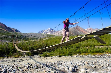 people scenic view sky hiking summer - A woman walks on a suspension bridge across College Creek to Gulkana Glacier, Southcentral Alaska, Summer/n Stock Photo - Rights-Managed, Code: 854-03645928