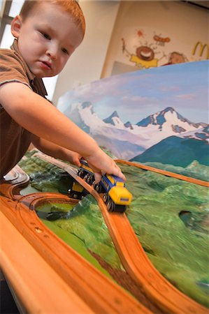 Toddler boy plays with a toy model of an Alaska Railroad train at the Imaginarium, Anchorage Museum at the Rasmuson Center, Southcentral Alaska, Summer Foto de stock - Con derechos protegidos, Código: 854-03740019