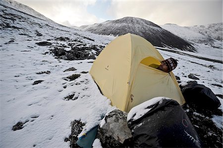 Backpacker sits inside a tent and waits out inclement weather at an alpine camp below Mt. Chamberln, Brooks Range, ANWR, Arctic Alaska, Summer Foto de stock - Con derechos protegidos, Código: 854-03740060