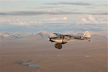 Aerial view of a Piper Super Cub airplane flying over the Jago River and tundra of the coastal plain in ANWR with the Romanzof Mountains in the background, Arctic Alaska, Summer Foto de stock - Con derechos protegidos, Código: 854-03740248
