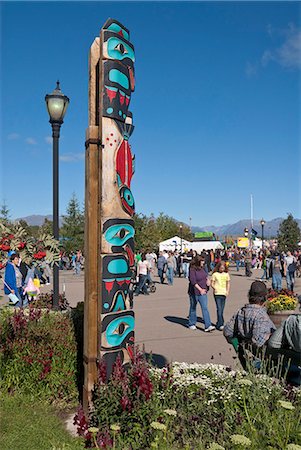 People walk by a totem pole near Raven Hall at Pioneer Plaza at the Alaska State Fair, Palmer, Southcentral Alaska, Autumn Stock Photo - Rights-Managed, Code: 854-03845177