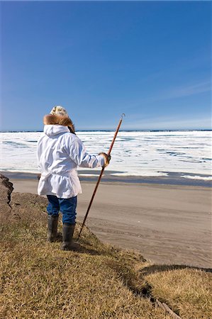 simsearch:851-02963922,k - Portrait d'un chasseur Inupiaq Eskimo mâle portant son parka Eskimo (Atigi) et un chapeau de peau de phoque et tenant un bâton de marche à Utkeagvik ancien lotissement original avec vue sur la mer des Tchouktches, Barrow, Alaska arctique, l'été Photographie de stock - Rights-Managed, Code: 854-03845469