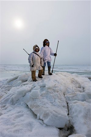 Männliche und weibliche Inupiak Eskimo Jäger tragen ihre Eskimo-Parka (Atigi) tragen ein Gewehr und Gehstock beim Blick auf die Tschuktschensee, Barrow, Alaska Arktis, Sommer Stockbilder - Lizenzpflichtiges, Bildnummer: 854-03845514