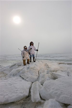 summer eskimo parka - Male and female Inupiaq Eskimo hunters wearing their Eskimo parka's (Atigi) carry a rifle and walking stick while looking out over the Chukchi Sea, Barrow, Arctic Alaska, Summer Stock Photo - Rights-Managed, Code: 854-03845516