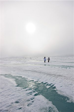 Zwei Inupiak Eskimo Jäger tragen ihre Eskimo-Parka (Atigi) ausführen ein Gewehr und Gehstock, während Sie zu Fuß über das Eis Ufer entlang der Tschuktschensee, Barrow, Alaska Arktis, Sommer Stockbilder - Lizenzpflichtiges, Bildnummer: 854-03845525
