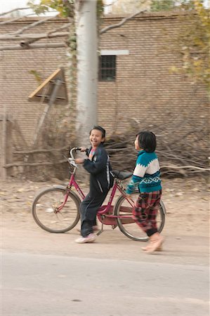 Uyghur girls playing with bicycle at the countryside of Kuche (Kuqa),Xinjiang,China Fotografie stock - Rights-Managed, Codice: 855-03026486