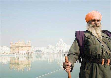 Sikh man standing near a pond with a temple in the background, Golden Temple, Amritsar, Punjab, India Foto de stock - Con derechos protegidos, Código: 857-03192894