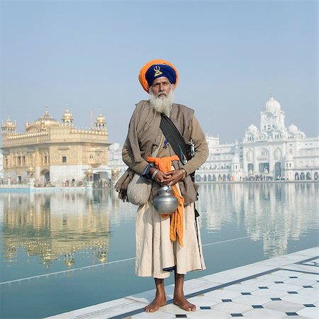 Sikh man in traditional clothing standing near a pond with a temple in the background, Golden Temple, Amritsar, Punjab, India Stock Photo - Rights-Managed, Code: 857-03192892