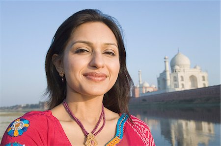 poses in saree for outdoor photography - Portrait of a woman with a mausoleum in the background, Taj Mahal, Agra, Uttar Pradesh, India Foto de stock - Con derechos protegidos, Código: 857-03193083