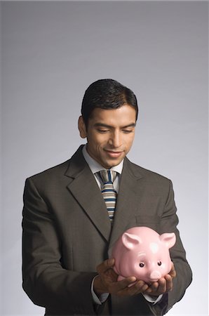 pig bank - Businessman holding a piggy bank Foto de stock - Con derechos protegidos, Código: 857-03554043