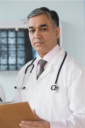 stethoscope check up indian photos - Portrait of a doctor holding a clipboard, Gurgaon, Haryana, India Stock Photo - Rights-Managed, Code: 857-03554137