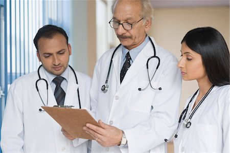 Three doctors examining a report, Gurgaon, Haryana, India Stock Photo - Rights-Managed, Code: 857-03554224