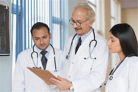 Three doctors examining a report, Gurgaon, Haryana, India Foto de stock - Con derechos protegidos, Código: 857-03554225