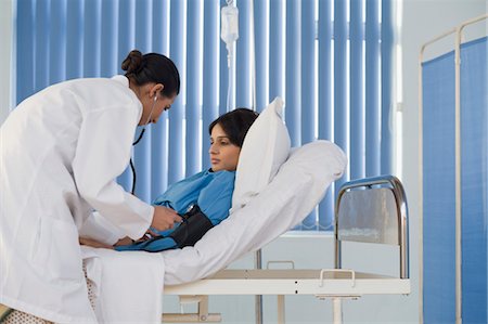 doctor caring for patient in a bed - Female doctor checking woman's blood pressure, Gurgaon, Haryana, India Stock Photo - Rights-Managed, Code: 857-03554262