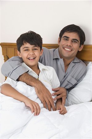 Man with his son smiling on the bed Foto de stock - Con derechos protegidos, Código: 857-03553778