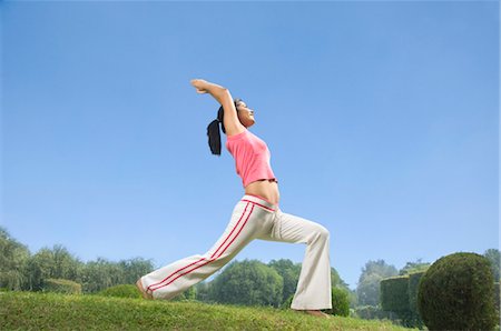 Woman practicing warrior 1 pose of yoga in a park, Gurgaon, Haryana, India Stock Photo - Rights-Managed, Code: 857-03553809