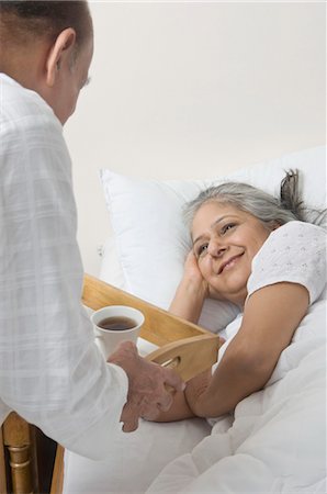 Man holding coffee tray near a woman lying on the bed Foto de stock - Con derechos protegidos, Código: 857-03553874