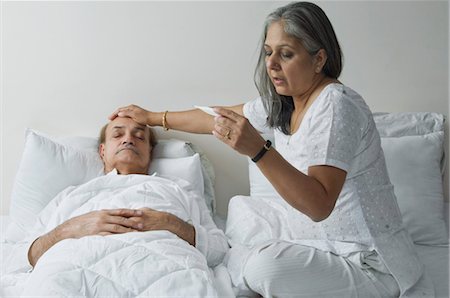 senior care touch - Woman checking a man's temperature in the bedroom Stock Photo - Rights-Managed, Code: 857-03553879