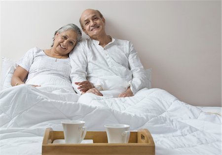 senior enjoying food - Couple sitting on the bed and smiling Stock Photo - Rights-Managed, Code: 857-03553873