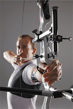 shooting arrow images - Male Archer Aiming With Bow And Arrow Stock Photo - Rights-Managed, Code: 858-06121545