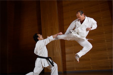 Two karate contestants directing kick at each other Fotografie stock - Rights-Managed, Codice: 858-03049817