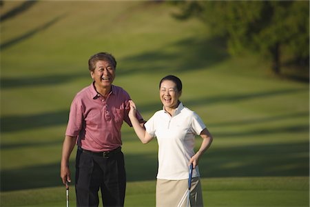 senior couple candid outdoors - Vue de face du sourire permanent de couple avec des clubs de golf Photographie de stock - Rights-Managed, Code: 858-03049933