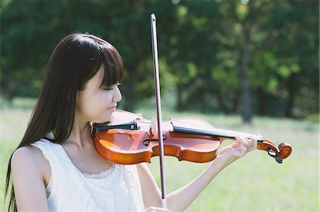 Portrait of an Asian woman playing the violin in a grass field Foto de stock - Con derechos protegidos, Código: 859-06404907